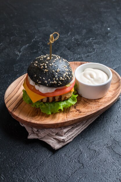 Selbst gemachter schwarzer Burger mit gegrilltem Hühnerpastetchen auf dunklem Hintergrund