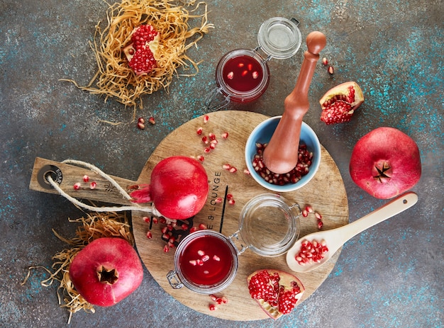 Selbst gemachter süßer roter Granatapfelsirup in Gläsern mit Granatapfelkernen auf einem Holzständer