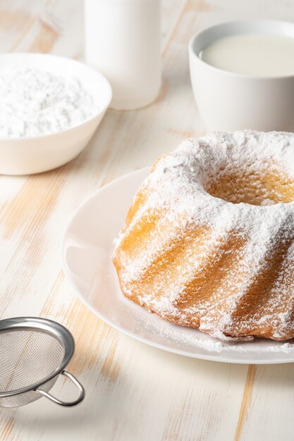 Selbst gemachter Vanillebundtkuchen auf weißem hölzernem Hintergrund.