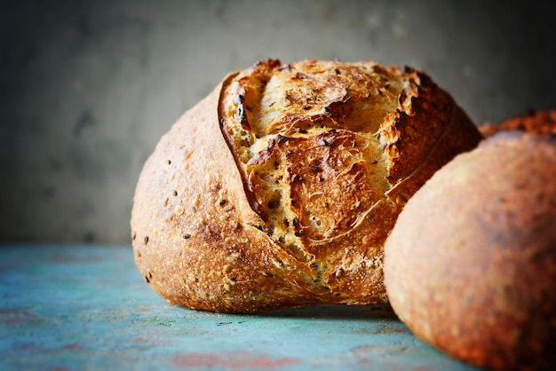 Selbst gemachtes frisch gebackenes Landbrot gemacht vom Weizen und vom Vollkornmehl auf einem grau-blauen Hintergrund