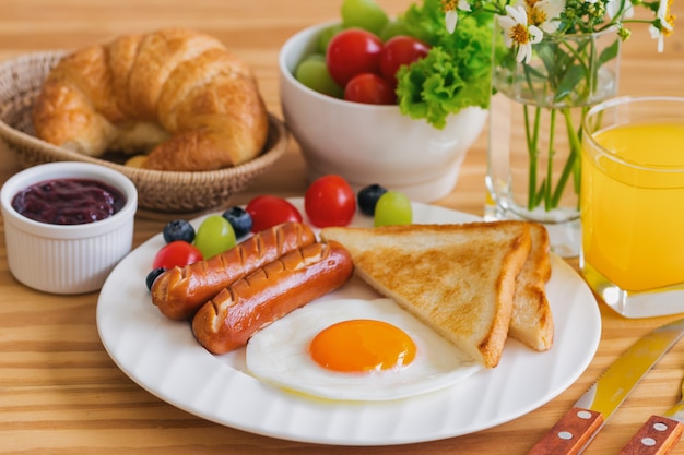 Selbst gemachtes Frühstück mit gebratener Eiertoastwurst trägt Gemüseerdbeermarmelade und Orange Früchte