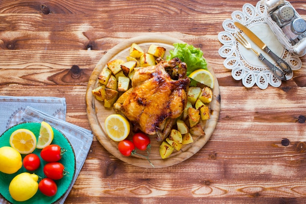 Selbst gemachtes gebackenes Huhn mit Zitrone und Kartoffeln auf einem Holztisch