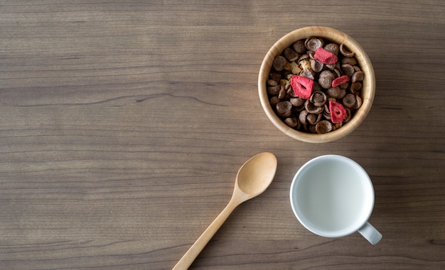 Selbst gemachtes Granola mit Milch zum Frühstück auf Holztisch. Ansicht von oben