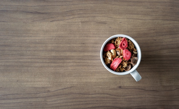 Selbst gemachtes Granola mit Milch zum Frühstück auf Holztisch. Ansicht von oben