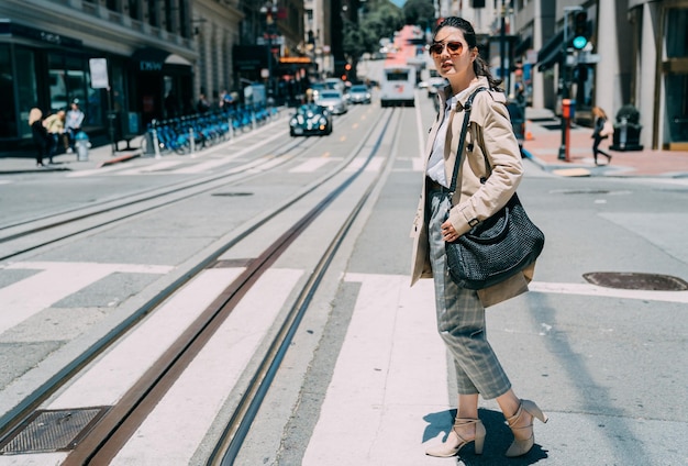 Selbstbewusste Anwältin konzentrierte sich am Sonnenscheintag auf die Überquerung der Zebrastraße in San Francisco City. Professionelle Geschäftsfrau mit Sonnenbrille, die auf dem Zebrastreifen spaziert. Street Cable Car in Kalifornien USA.