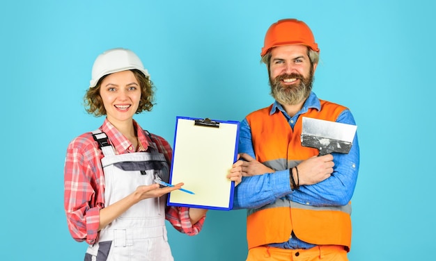 Selbstbewusste Elektro- und Technikerpaare, die gemeinsam an Bauplänen auf der Baustelle oder in der Fabrik arbeiten