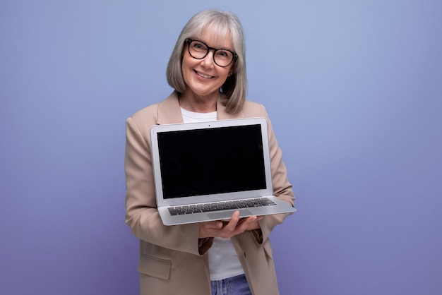 Selbstbewusste erwachsene Frau in einer Jacke mit einem Laptop auf einem hellen Hintergrund mit Kopierplatz