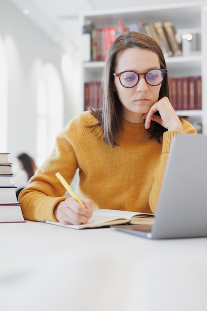 Selbstbewusste Frau arbeitet in der Bibliothek im Coworking am Laptop oder im Büro Studentin studiert online