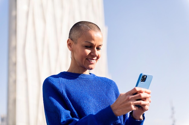 Selbstbewusste Frau im blauen Pullover benutzt Mobiltelefon