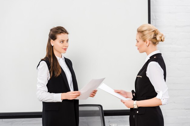 selbstbewusste junge Geschäftsfrauen mit Dokumenten in einem modernen Büro