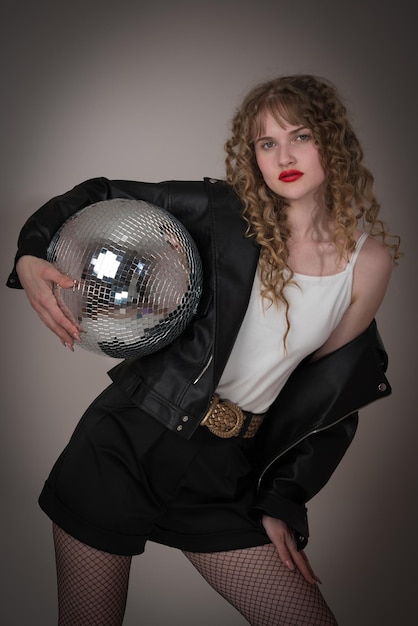 Selbstbewusste Tänzerin hält einen Disco-Ball Frau strahlt während einer Nachtclub-Party eine Sensualität aus