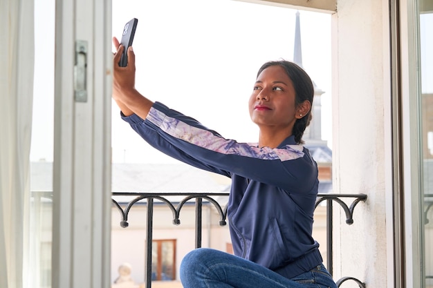 Selbstbewusste und kreative junge Inderin macht ein stilvolles Selfie von ihrer Fensterbank