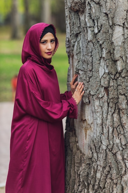 Selbstbewusster arabischer Geschäftsmann, der lächelt und durch Dubai geht Arabisches Geschäft Vumen Hijab ist in den Straßen gegen die Wolkenkratzer von Dubai die Frau ist in einer schwarzen Abaya gekleidet