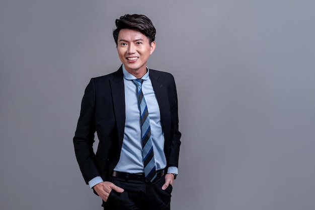 Selbstbewusster asiatischer Geschäftsmann posiert auf einem isolierten Hintergrund Jubilant