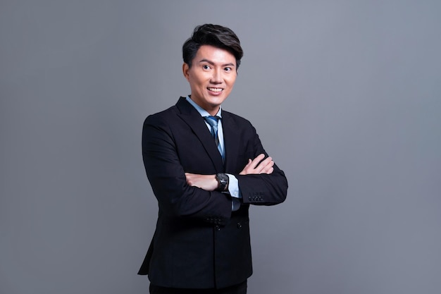 Selbstbewusster asiatischer Geschäftsmann posiert jubelnd vor isoliertem Hintergrund