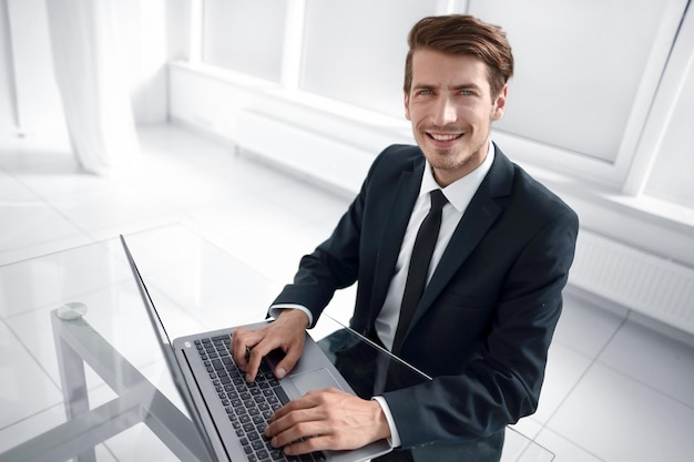 Selbstbewusster Geschäftsmann, der im Büro Deskphoto mit Kopierbereich sitzt