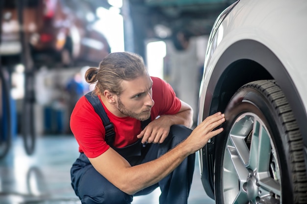 Selbstbewusster junger erwachsener Mann in der Arbeitsuniform, die an Autos arbeitet