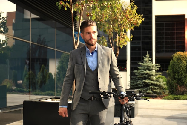 Selbstbewusster junger Geschäftsmann, der mit dem Fahrrad auf der Straße in der Stadt spazieren geht
