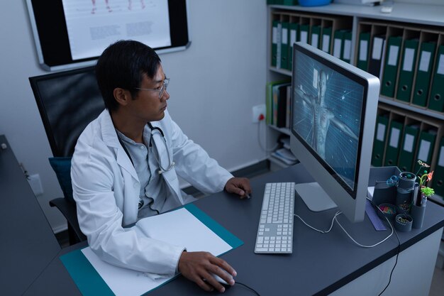 Selbstbewusster männlicher Arzt, der in einer Klinik am Computer arbeitet