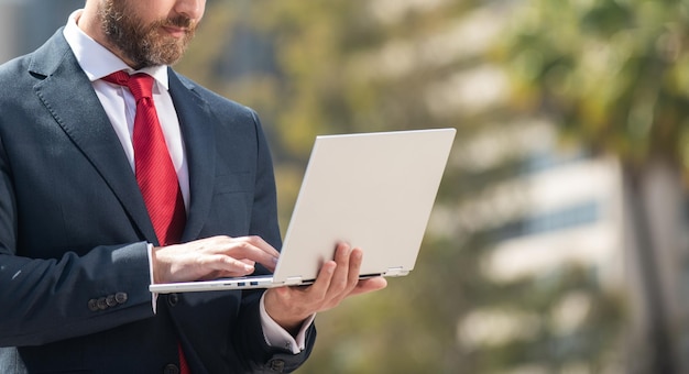 Selbstbewusster Mann im eleganten Anzug, der auf dem PC außerhalb des Kopierraumnetzwerks tippt