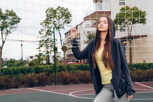 Selbstbewusstes junges Mädchen, das Volleyball auf dem Sportplatz im Freien spielt