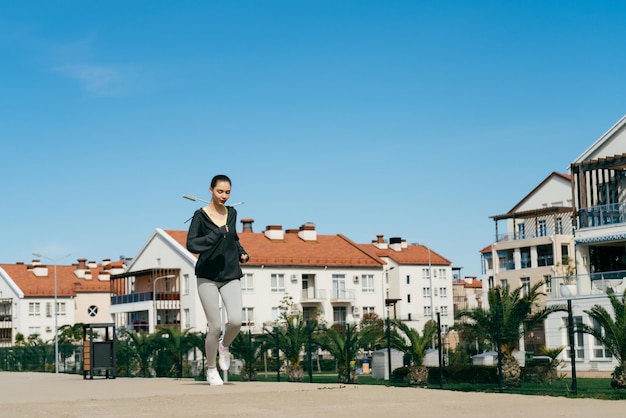 Selbstbewusstes junges Mädchen joggt unter blauem Himmel und führt einen aktiven und gesunden Lebensstil