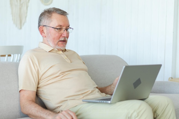 Selbstbewusstes, stilvolles, glückliches, mittelalterliches, älteres Mann, das zu Hause einen Laptop benutzt. Stilvolles, älteres, reiferes Bart.