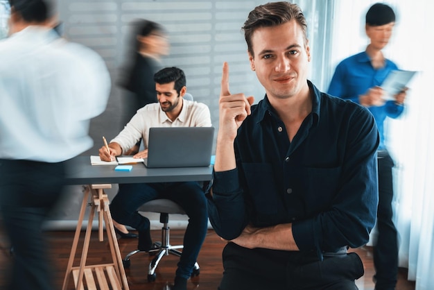 Foto selbstvertrauen und glückliches lächelndes geschäftsmannporträt mit verschwommenem hintergrund seines kollegen und des geschäftsteams, das im büro arbeitet büroangestellter teamarbeit und positives arbeitsplatzkonzept vorsichtig