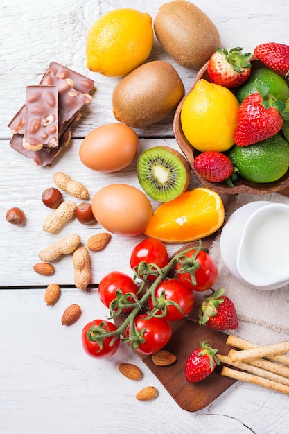 Seleção de alimentos para alergia laranja suco cítrico leite tomate vermelho morango kiwi ovos chocolate nozes pão glúten em uma mesa de madeira rústica Vista superior plana em cima