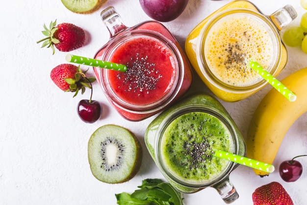 Seleção de smoothies de frutas multicoloridas em frascos de vidro.