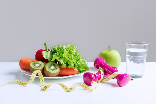 Selección de alimentos saludables con frutas, verduras y artículos para perder peso en el fondo de la tabla blanca