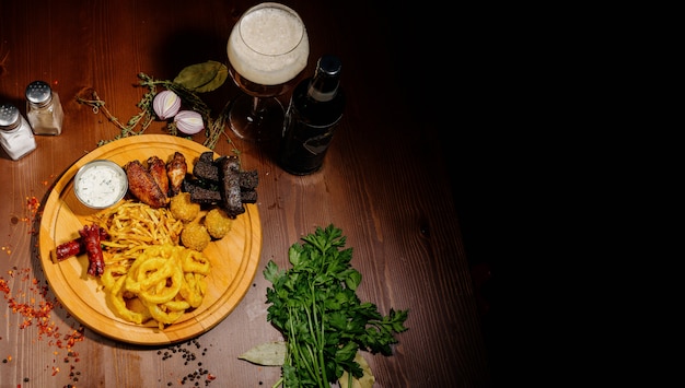 Foto selección de cervezas y snacks. patatas fritas, pescado, salchichas de cerveza en la mesa