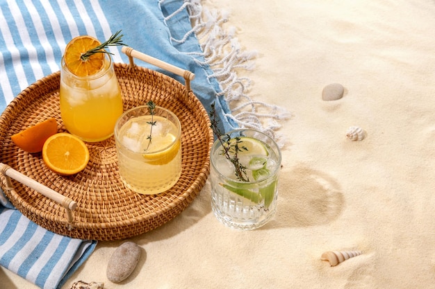 Selección de cócteles alcohólicos de verano en una bandeja de mimbre en la playa con arena blanca Vacaciones de verano en el mar y concepto de viaje Bebidas exóticas de verano