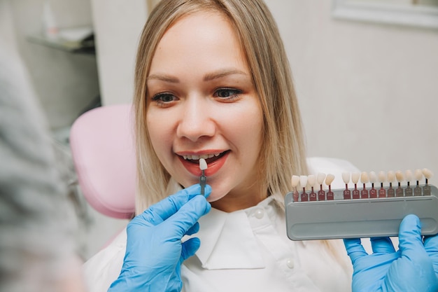 Selección del color de diente correcto para el blanqueamiento cosmético profesional en el dentista. el médico selecciona los dientes para el paciente.