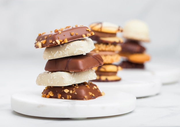 Selección de galletas de chocolate y galletas belgas de lujo en posavasos de mármol y mesa de cocina.