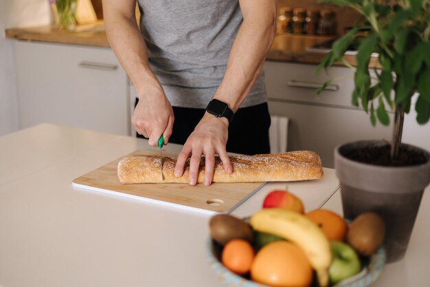 Foto selección media de baguette en rodajas de hombre sobre mesa de madera en la cocina