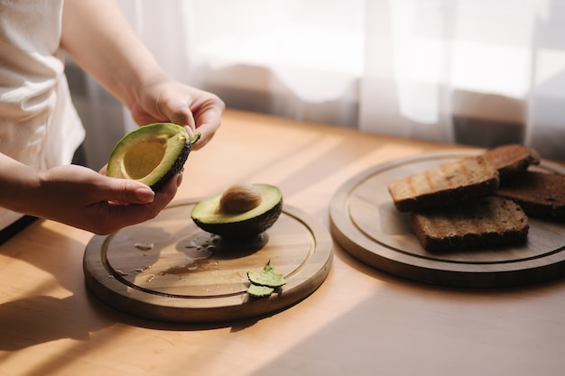 Selección media de píldora femenina un aguacate sobre tabla de madera en casa. Concepto de comida vegetariana.