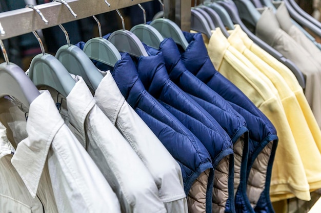 Una selección de ropa informal para hombres en perchas en una tienda Camisas, chaquetas y camisetas en perchas Estilo y moda Primer plano