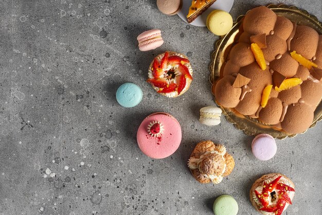 Selección de varios trozos de pastel Choux pasteles macarons pastel de terciopelo de chocolate sobre un fondo de piedra gris