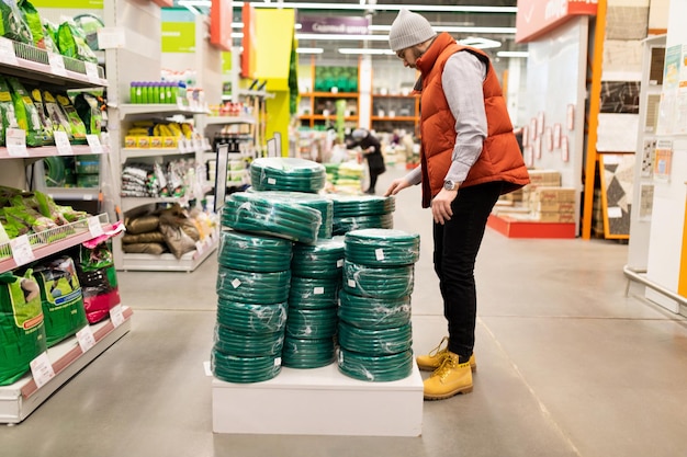 Se selecciona a un hombre en un hipermercado de jardín con una manguera para el trabajo de riego