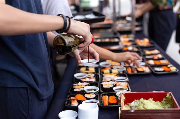 Seleccionado foco mano vierte salsa de sushi con wasabi en tailandia comida callejera sushi japonés