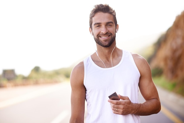 Selecionando um álbum para acompanhá-lo em sua corrida Retrato de um jovem bonito ao ar livre com um MP3 player