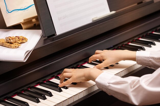 Selektive Fokusmusikkomposition Ein Junge spielt elektronisches Klavier mit Noten und Granola-Zerealien-Riegeln Klavier-Heimunterricht Musikbildung köstlicher hausgemachter Snack während der Ausbildung