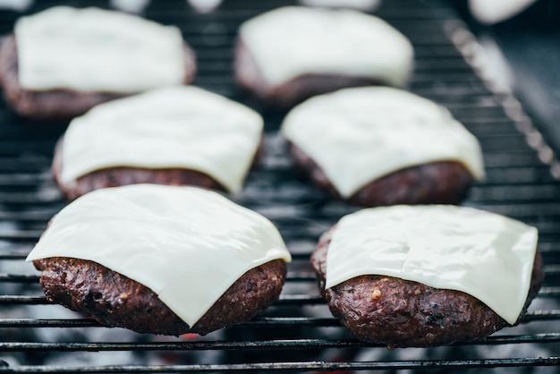 Selektive Fokussierung auf frische, köstliche Burgerkoteletts mit Käsegrillen auf dem Grillrost