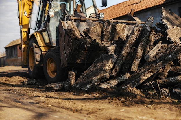 Selektiver Fokus auf Bagger, die Asphalthaufen auf der Baustelle sammeln