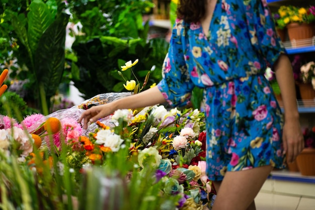 Selektiver Fokus auf Blumen und Pflanzen eines Blumenladens mit einer Frau im Sommerkleid kaufen