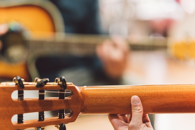 Selektiver Fokus auf die Hände einer Frau, die im Duett mit einem alten Mann Gitarre spielt.