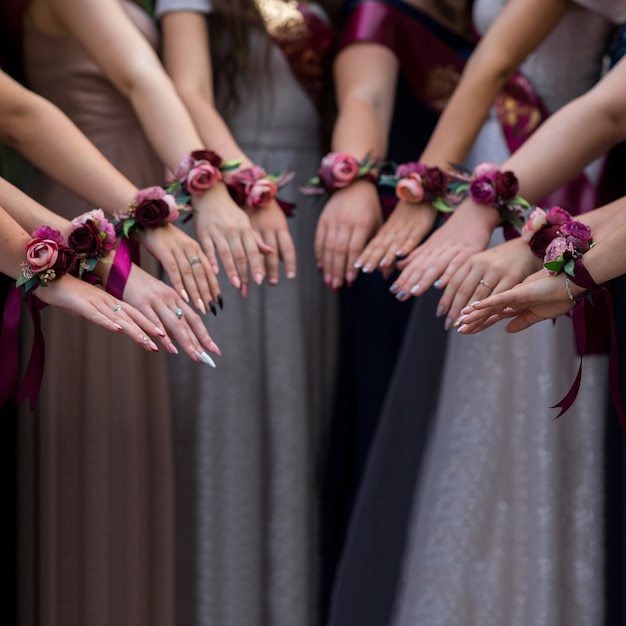 Selektiver Fokus auf die Hände einer Gruppe von Mädchen mit Boutannieres. schöne Blumendekorationen für Hände