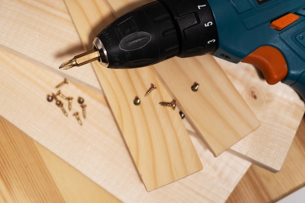 Selektiver Fokus auf Schraubendreher und selbstschneidende Schrauben, die auf Holzbrettern und Latten liegen, Nahaufnahme von Tischlerarbeiten