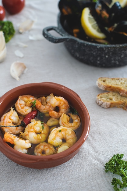 Foto selektiver fokus auf traditionelle spanische knoblauchgarnelen, gebraten in würzigem olivenöl mit petersilie